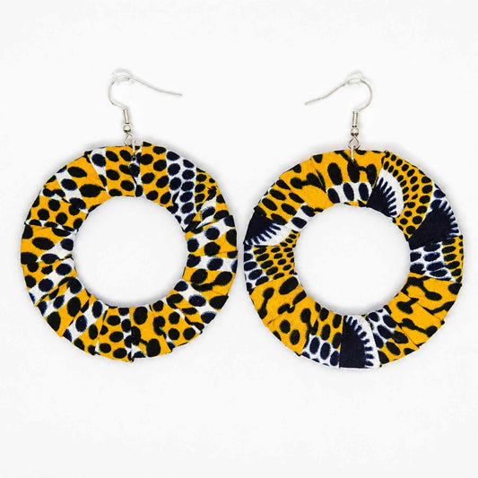 Paire de boucles d'oreilles artisanales en tissu wax africain, forme cercle ajouré, motif léopard jaune soleil, pois noirs et motifs éventail marine et blanc — vue produit