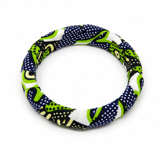 Bracelet jonc rond en bois recouvert de tissu wax vert et bleu marine à motifs de pois, isolé sur fond blanc.