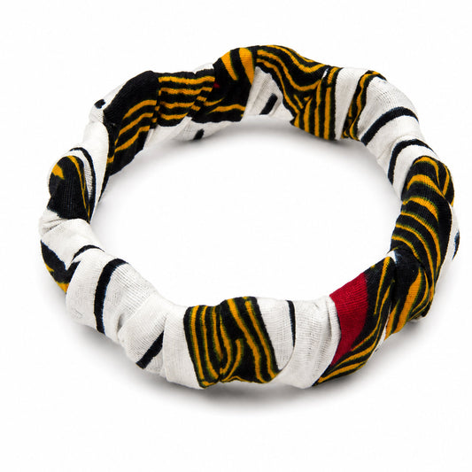 Bracelet jonc ondulé en bois recouvert de tissu wax blanc à rayures noires et jaunes avec touche de rouge, isolé sur fond blanc.