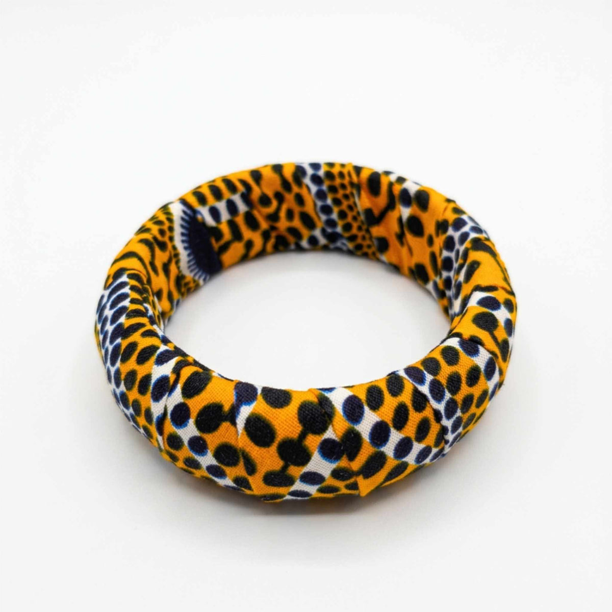 Bracelet jonc en tissu wax artisanal aux nuances jaune moutarde et noir à motifs pois et écailles.