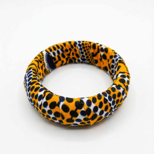 Bracelet jonc en tissu wax artisanal aux nuances jaune moutarde et noir à motifs pois et écailles.