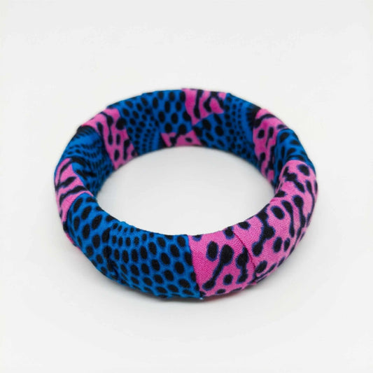 Bracelet jonc rigide habillé de tissu wax rose fuchsia et bleu intense à motifs tachetés.