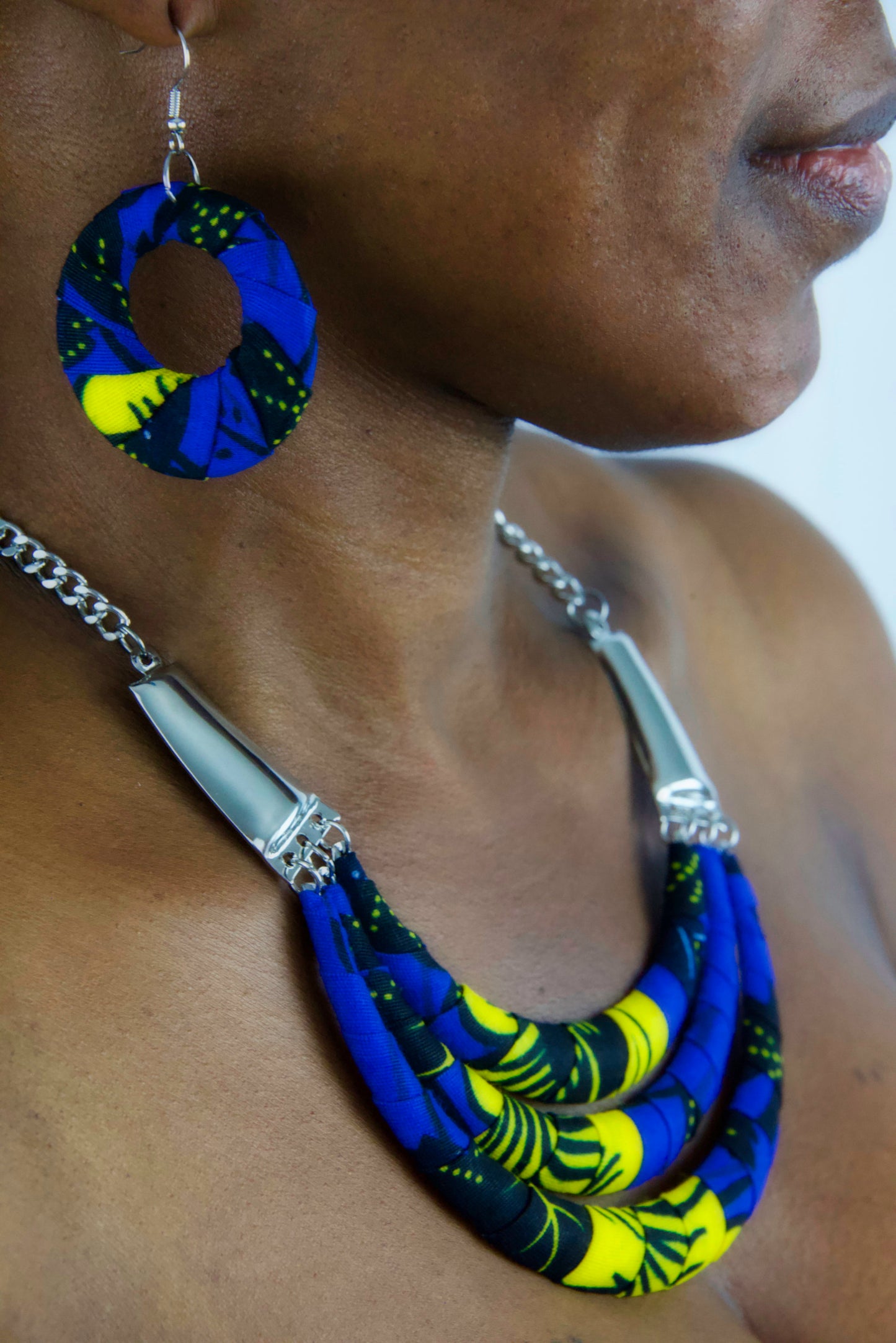 Femme portant une Parure bijoux fantaisie en tissu wax bleu jaune et noir
