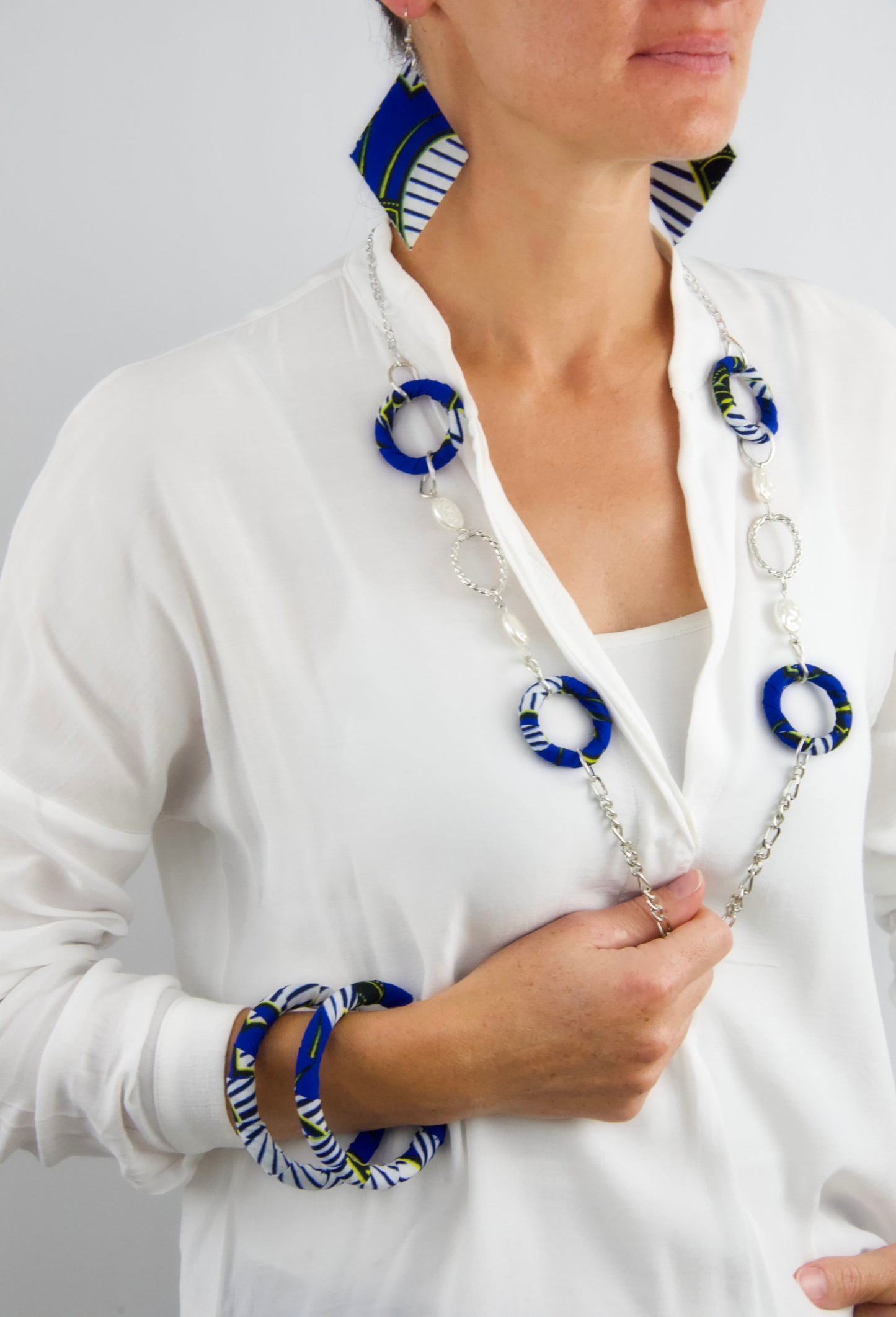 Femme portant une Parure bijoux wax sautoir bleu blanc jaune noir - collier long bracelets boucles d'oreilles - tissu recyclé artisanal