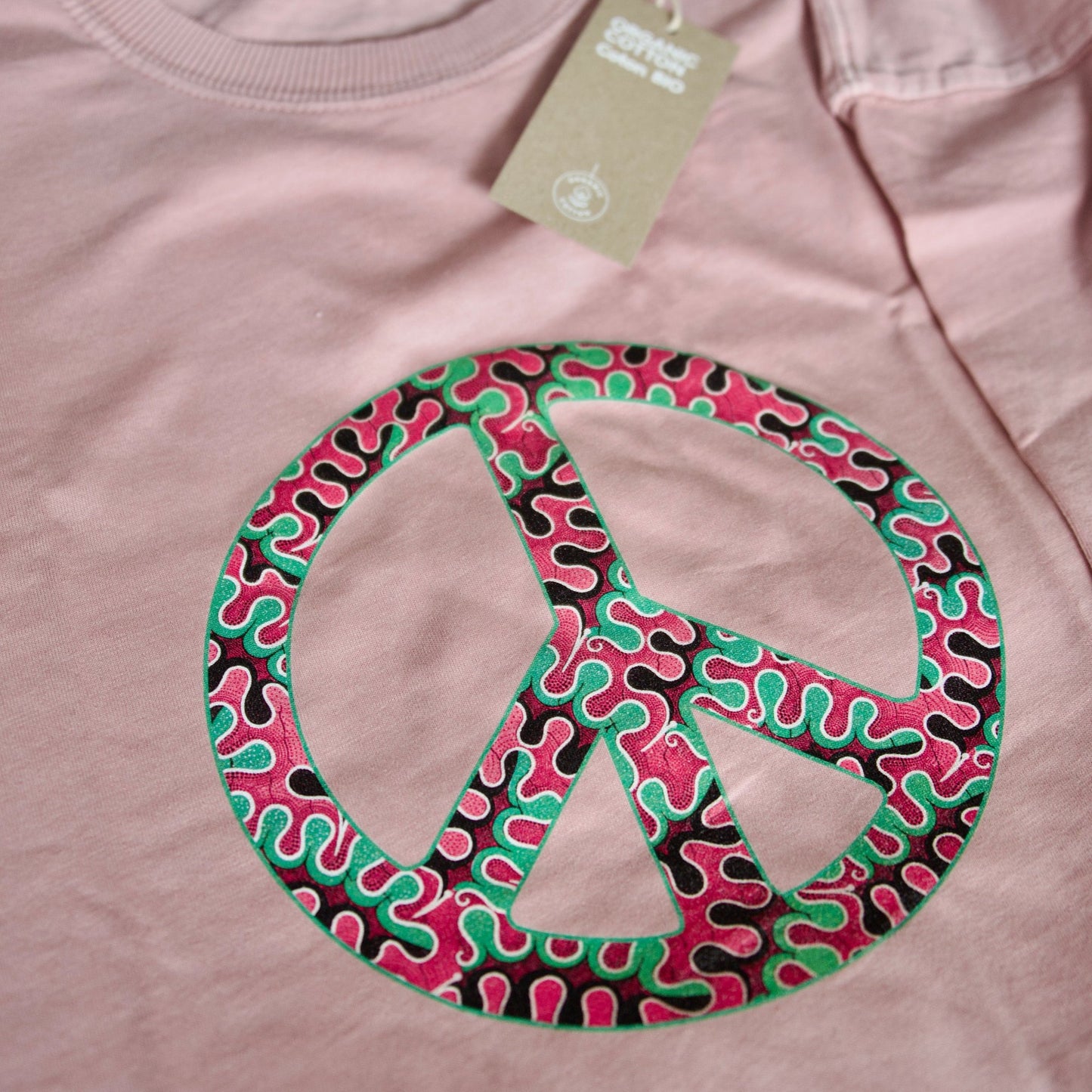 Gros plan du motif wax Peace & Love sur robe T-shirt pétale rose