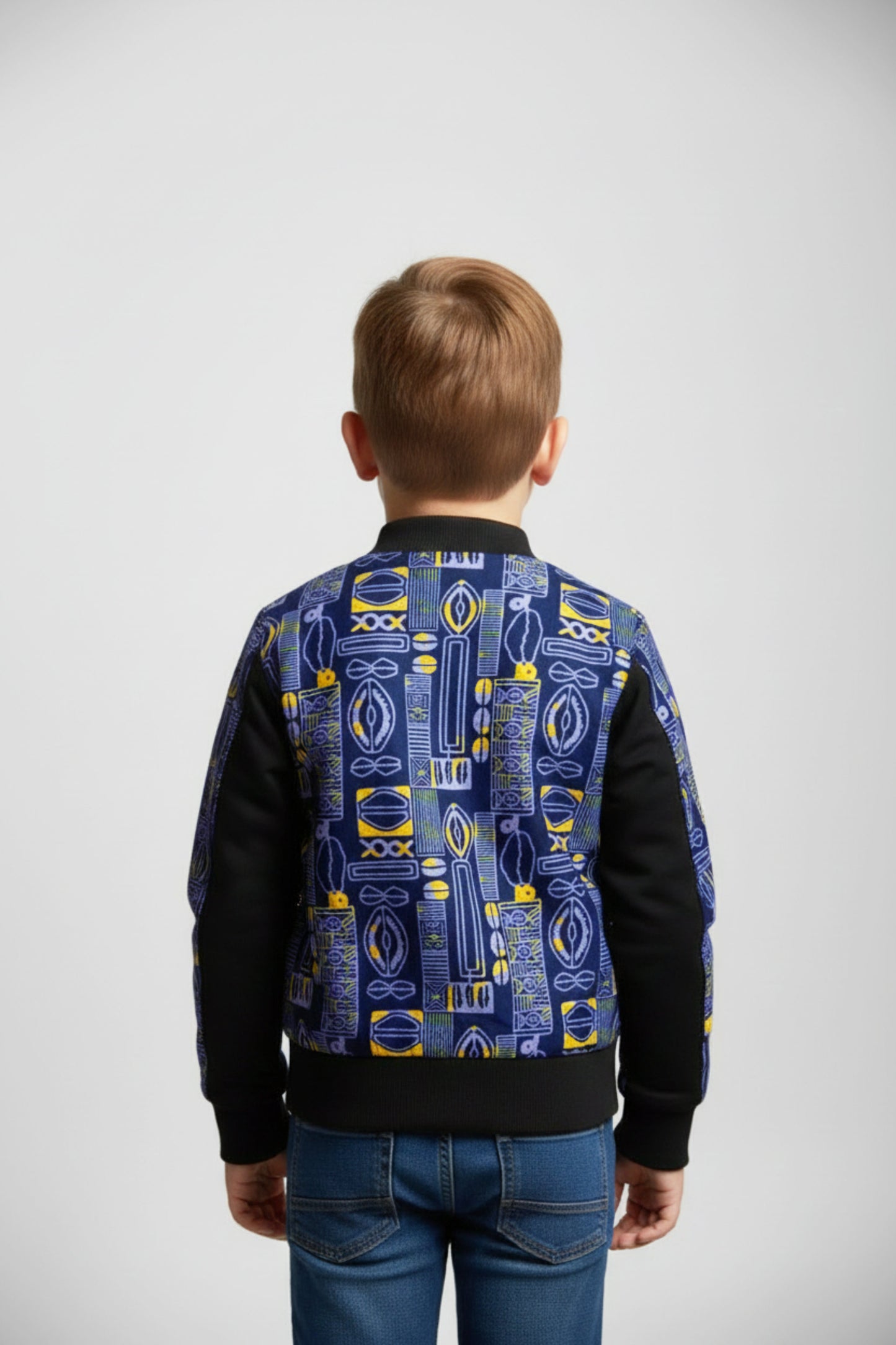 Vue dos garçon portant un bomber jacket en tissu wax bleu marine à motifs Adinkra jaune et blanc avec manches côtelées noires - Vêtement enfant africain fait main Djêkoo Wax