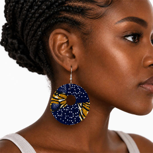 Boucles d'oreilles pendantes artisanales en tissu wax africain, forme cercle ajouré, motif marine profond à pois blancs et ocre doré — portées en situation
