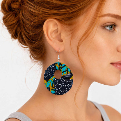Boucles d'oreilles pendantes artisanales en tissu wax africain, forme cercle ajouré, motif multicolore marine, turquoise, vert anis et pois blancs — portées en situation