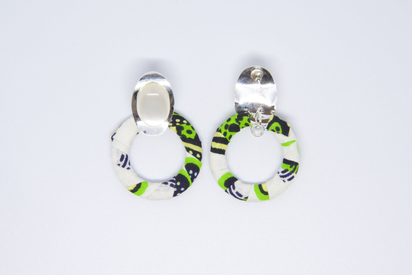 Vue dos boucles d'oreilles créoles artisanales recouvertes de tissu wax vert anis, noir et blanc avec cabochon ovale argenté et système clip - Bijou africain fait main Djêkoo Wax