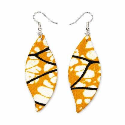 Paire de boucles d'oreilles artisanales en tissu wax africain, forme feuille, motif graphique orange, taches blanches et lignes noires — vue recto