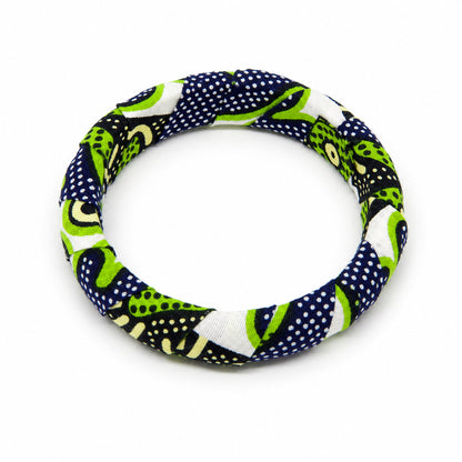 Bracelet jonc rond en bois recouvert de tissu wax vert et bleu marine à motifs de pois, isolé sur fond blanc.
