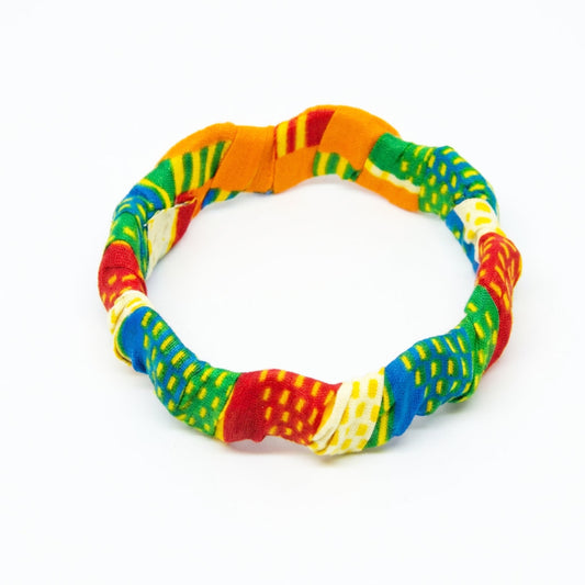 Bracelet jonc ondulé en bois recouvert de tissu wax multicolore aux nuances d'orange, vert, bleu et rouge, isolé sur fond blanc.