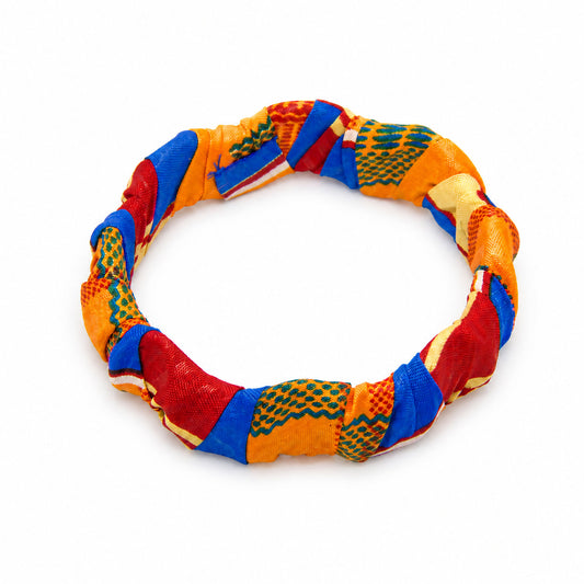 Bracelet jonc ondulé en bois recouvert de tissu wax aux motifs géométriques orange, rouge et bleu royal, isolé sur fond blanc.