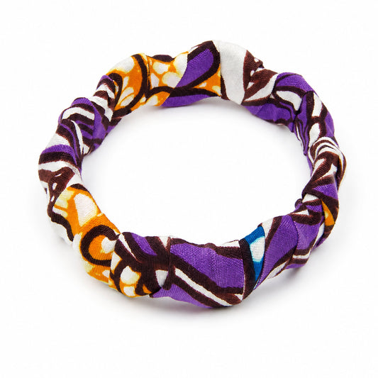 Bracelet jonc ondulé en bois recouvert de tissu wax violet et orange aux motifs graphiques, isolé sur fond blanc.