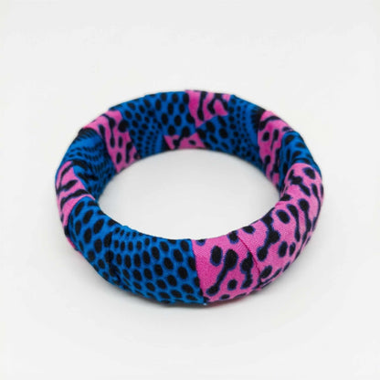 Bracelet jonc rigide habillé de tissu wax rose fuchsia et bleu intense à motifs tachetés.