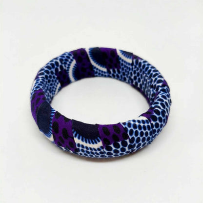 Bracelet jonc rigide artisanal recouvert de tissu wax aux motifs alvéolés violet, indigo et blanc, confectionné en France.