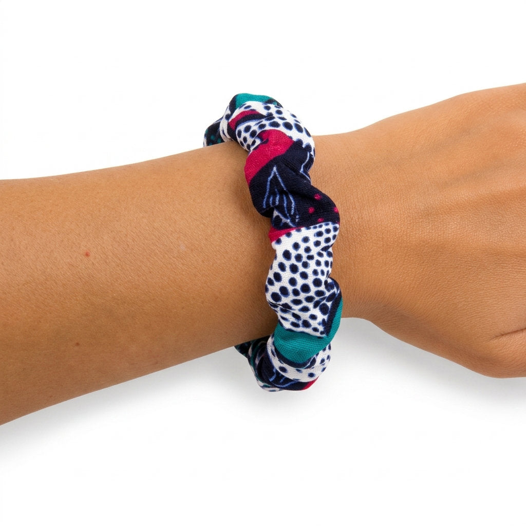 Bracelet jonc torsadé artisanal en tissu wax africain, motif graphique marine rose fuchsia et vert émeraude — porté au poignet