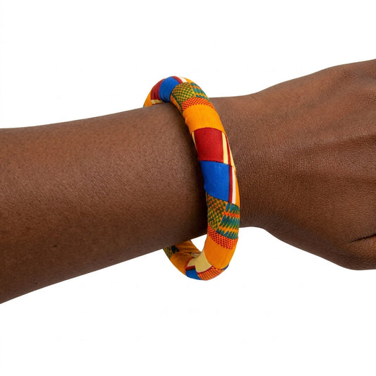 Bracelet en tissu wax orange, rouge, bleu et vert porté au poignet.