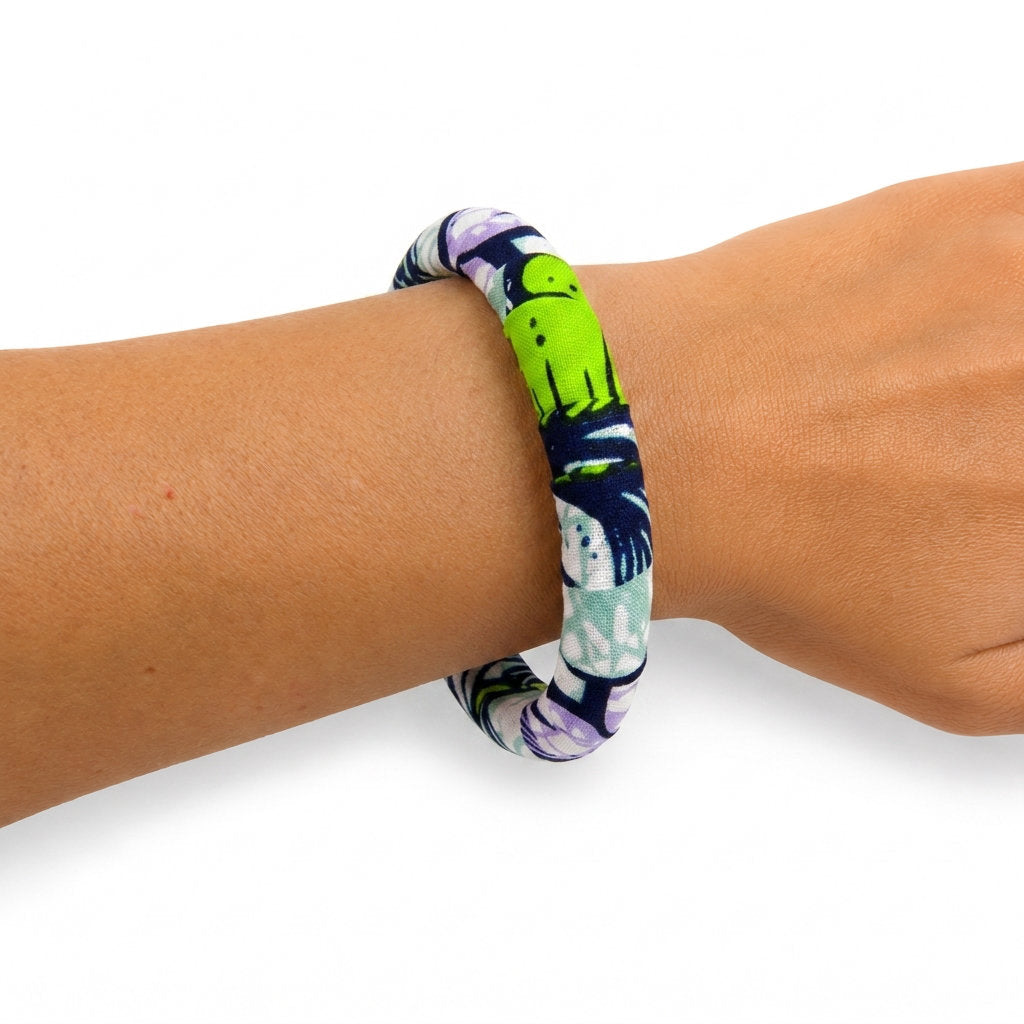 Bracelet en tissu wax vert, bleu marine et violet porté au poignet.
