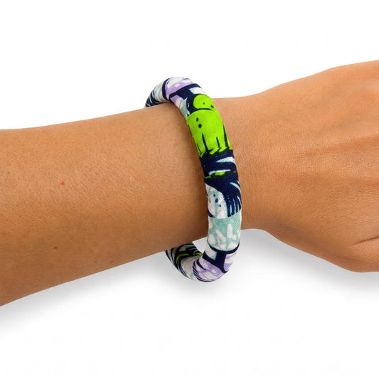 Bracelet en tissu wax vert, bleu marine et violet porté au poignet.
