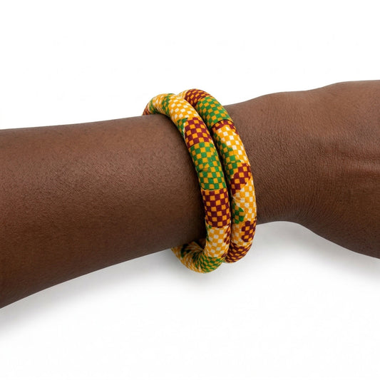 Duo de bracelets joncs rigides recouverts de tissu wax orange rouge et vert aux motifs damier, porté au poignet sur fond blanc.