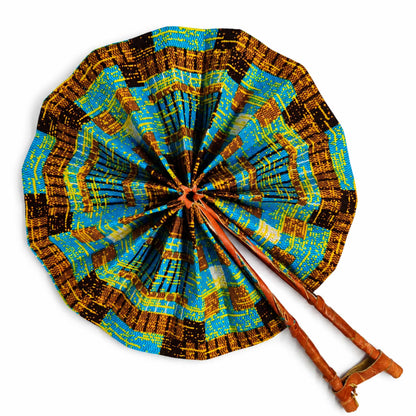 Éventail africain artisanal ouvert, en tissu wax bleu turquoise, jaune et marron, avec structure et manche en bois, sur fond blanc.