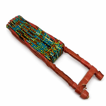 Éventail africain pliable présenté fermé, en tissu wax bleu, jaune et marron, avec manche artisanal en bois gainé de cuir.