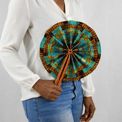 Éventail africain artisanal rond en wax bleu, jaune et marron, présenté ouvert et tenu à la main avec une tenue blanche et un jean.