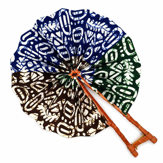 Éventail africain artisanal ouvert en tissu wax bleu, vert, marron et blanc, avec motifs graphiques et structure en bois, sur fond blanc.