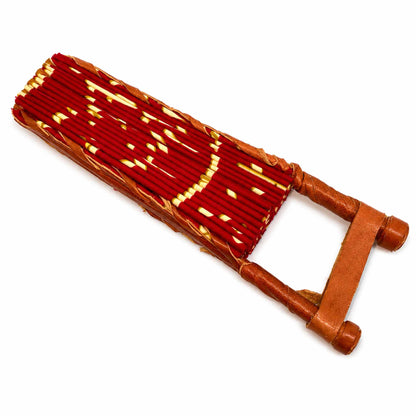 Éventail africain pliable présenté fermé, en tissu wax rouge à motifs jaunes, avec structure en bois et finitions en cuir, sur fond blanc.