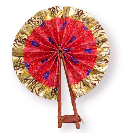 Éventail africain pliable ouvert en tissu wax doré à motifs géométriques Bogolan marron avec centre en tissu wax rouge à fleurs violettes et manche en cuir tressé terracotta - Accessoire artisanal Djêkoo Wax