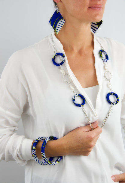 Femme portant une Parure bijoux wax sautoir bleu blanc jaune noir - collier long bracelets boucles d'oreilles - tissu recyclé artisanal