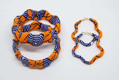 Parure Nina artisanale composée de boucles d’oreilles et bracelets en wax orange, bleu marine, blanc et noir.