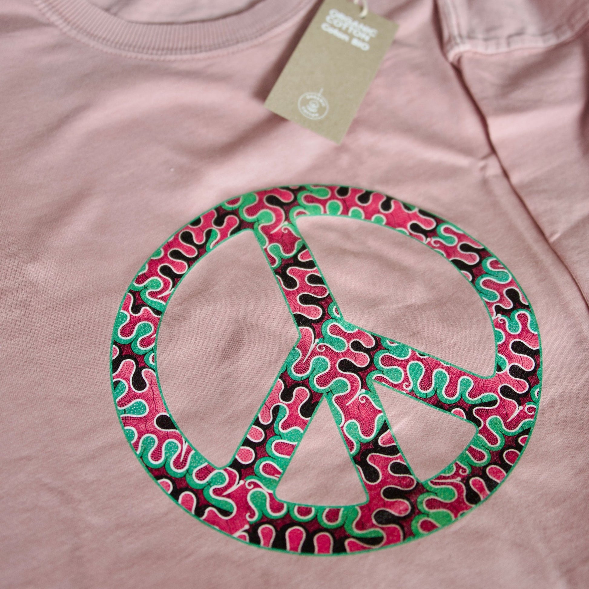 Gros plan du motif wax Peace & Love sur robe T-shirt pétale rose