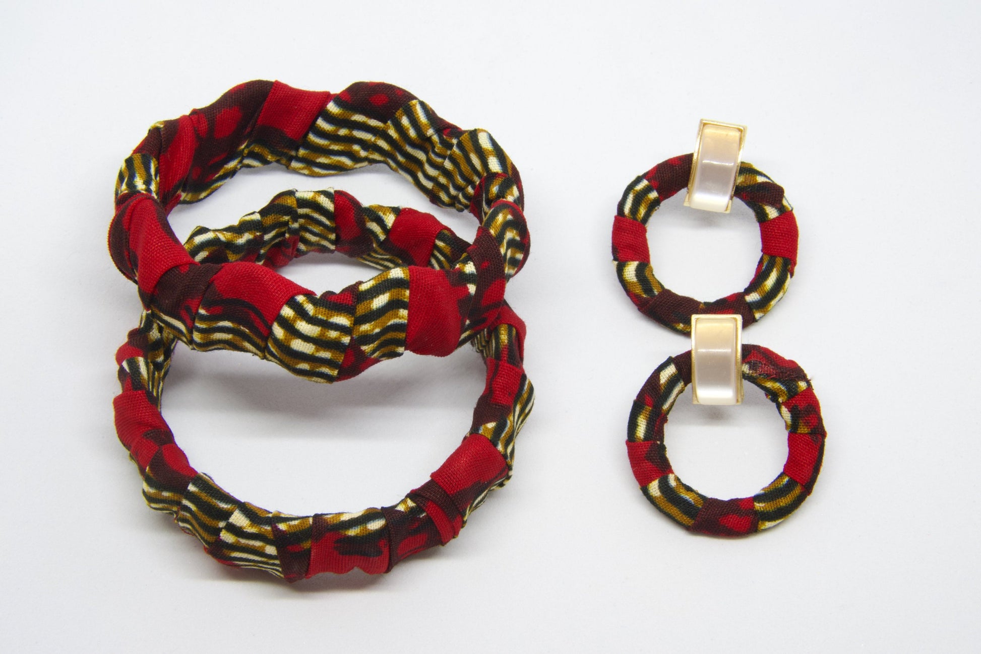 Set de bijoux artisanaux en tissu wax rouge bordeaux à motifs rayures diagonales doré kaki et noir comprenant deux bracelets torsadés rigides et une paire de boucles d'oreilles créoles rondes avec clip rectangulaire doré nacré - Bijoux africains Djêkoo Wax


