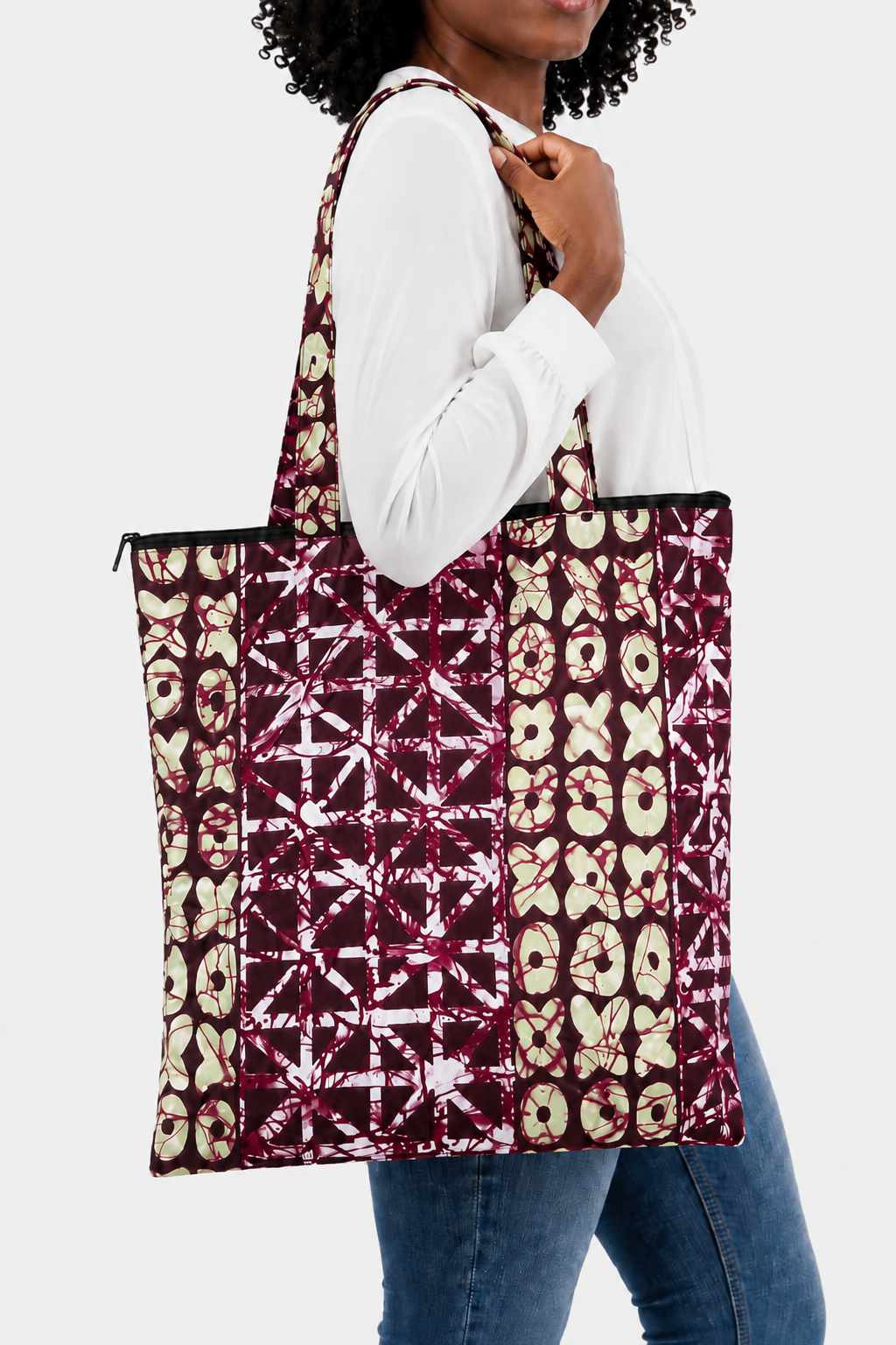 Tote bag artisanal fait main en tissu wax motif Batik bordeaux, beige et blanc, porté à l’épaule, avec longues anses et fermeture zippée