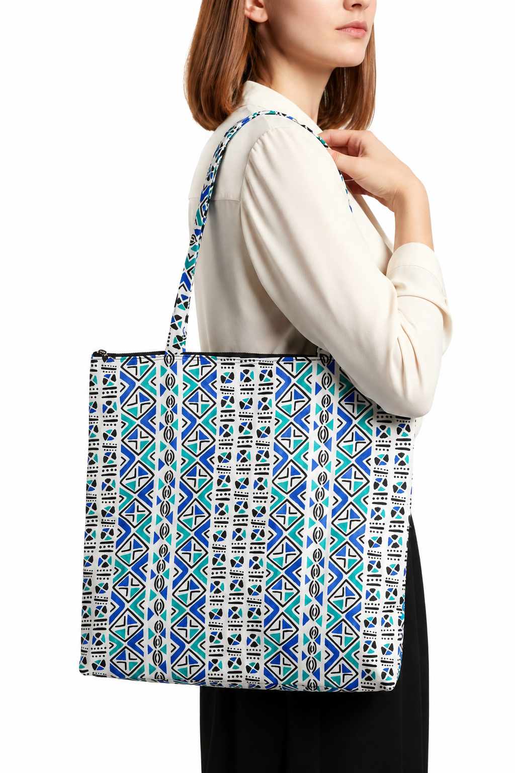 Tote bag artisanal en tissu wax blanc à motif Bogolan bleu, vert et noir, porté à l’épaule, avec longues anses et fermeture zippée